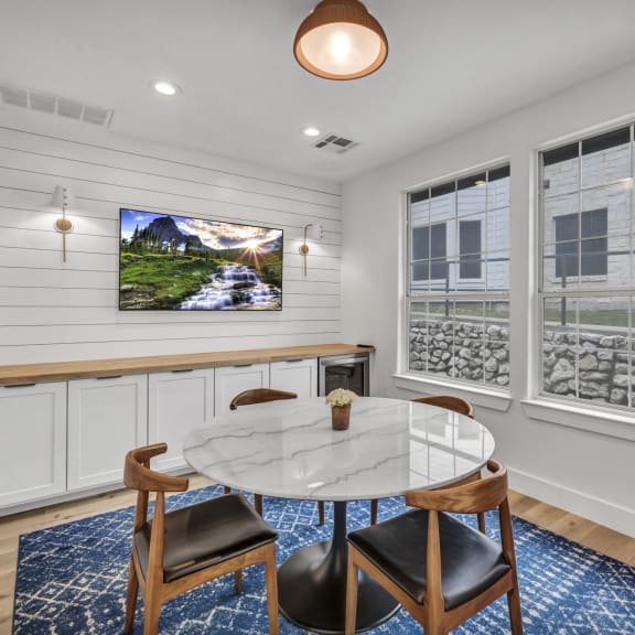 a dining room with a table and chairs and a tv on the wall