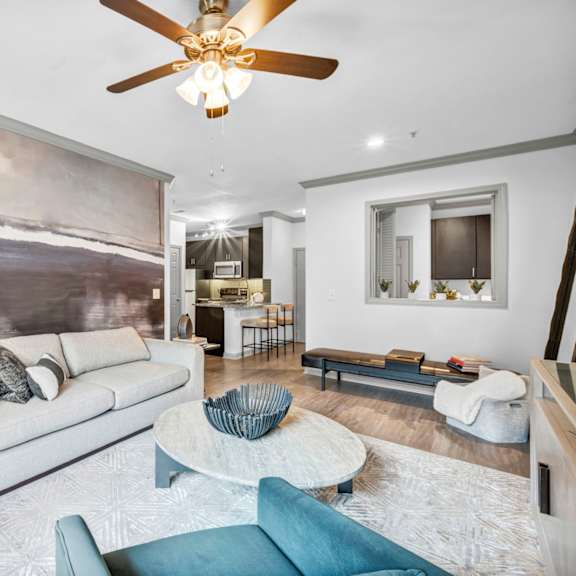 A modern living room with a large painting on the wall and a ceiling fan.