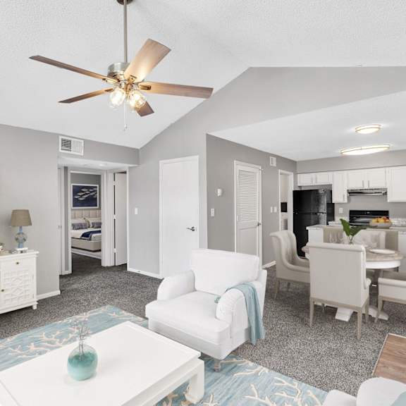 A living room with a ceiling fan and a dining area.