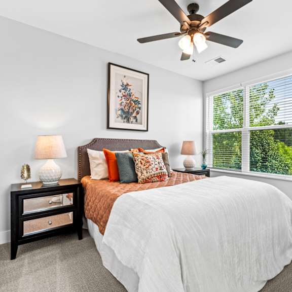 A bedroom with a bed, nightstand, and a ceiling fan.
