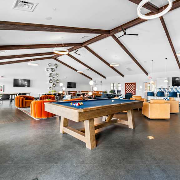 A pool table in a room with a couch and a window.