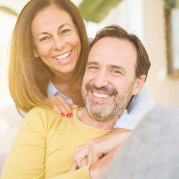 A man and a woman are sitting closely together, sharing a warm, affectionate moment.