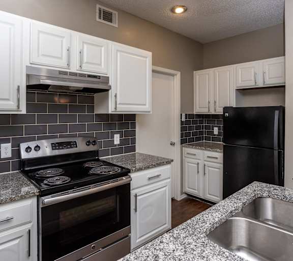 an empty kitchen with white cabinets and black appliances
