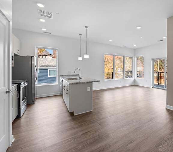 A spacious kitchen with a refrigerator, sink, and cabinets.at The Lumos Apartments in Cleveland, OH