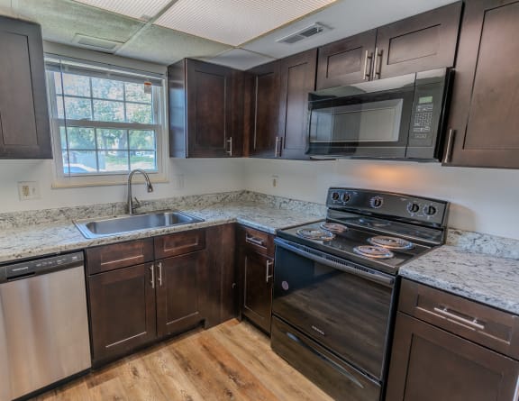 a kitchen with dark wood cabinets and granite counter tops and a stove and microwave