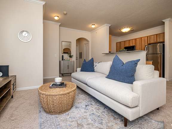 A living room with a white couch and a wicker coffee table.
