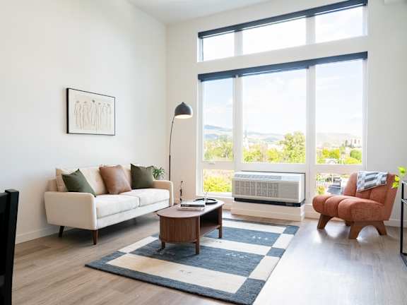 A living room with a couch, a table, and a large window.