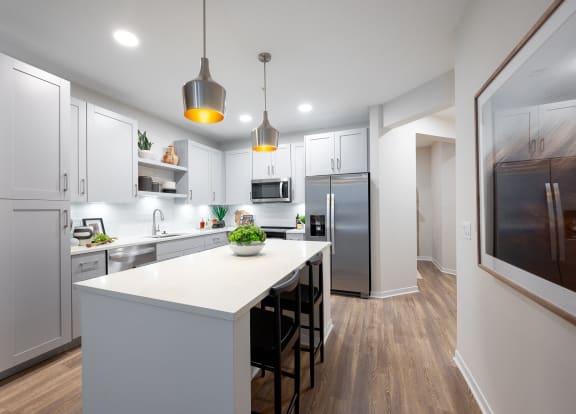 a large white kitchen with stainless steel appliances and a white counter top
