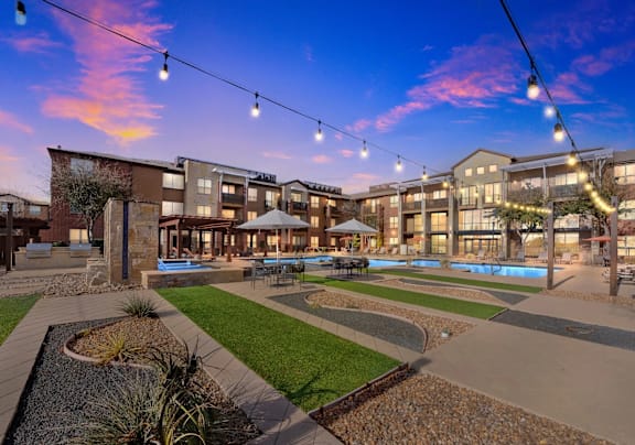 A sunset view of a courtyard with a pool and apartment buildings.