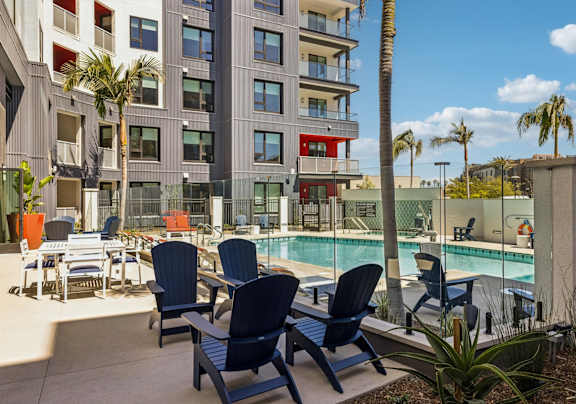 A poolside area with chairs and a pool in front of a multi-story building.at Panorama Riverpark, Oxnard, CA