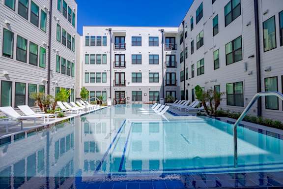A swimming pool in front of a white building with a blue sky in the background.