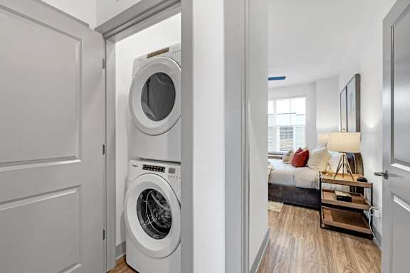 a front loading washer and dryer in a living room with a bedroom at Meridian at CityPlace in Woodbury, MN