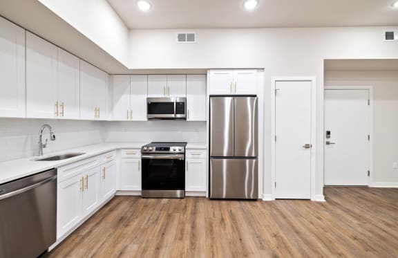 an empty kitchen with white cabinets and stainless steel appliances