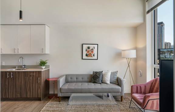 A modern kitchen with stainless steel appliances and a dining area with a grey couch.