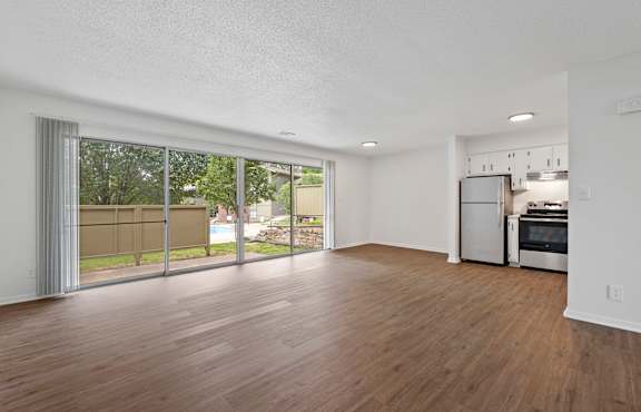 A spacious living room with a kitchen in the background.