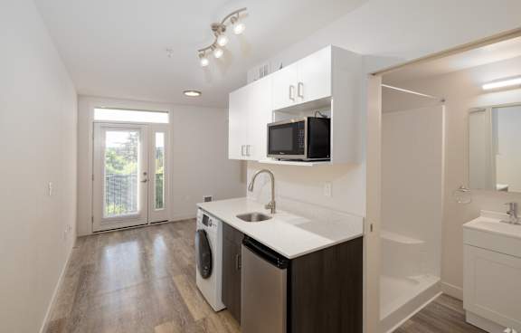 Modern studio kitchen with stainless steel refrigerator, microwave, and a washer/dryer combo