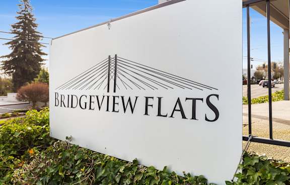 A white sign with the words "Bridgeview Flats" and a logo of a bridge.