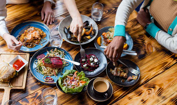 A group of people enjoying a meal together at a wooden table. at Chapman House, E. Boston, MA