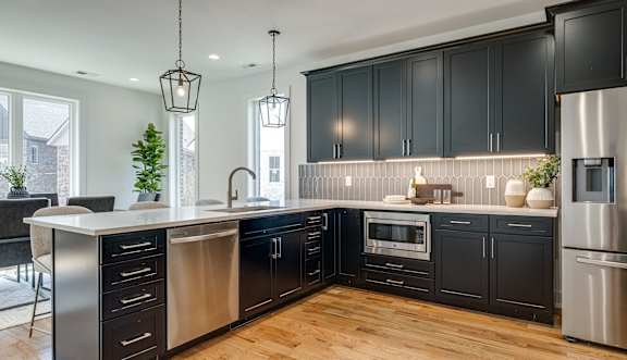 A modern kitchen with black cabinets and stainless steel appliances.