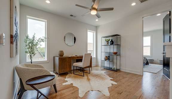 A room with a chair, desk, and a mirror on the wall.