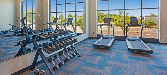 a gym with weights and other exercise equipment in a room with windows