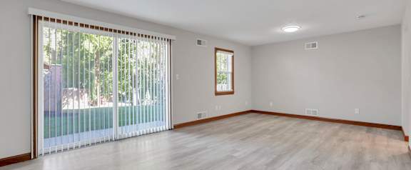 A room with a sliding glass door and wooden flooring.
