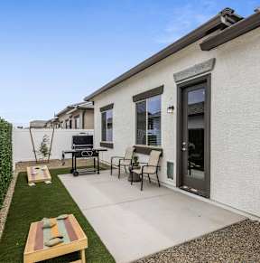 A patio with a table and chairs is surrounded by a white fence.