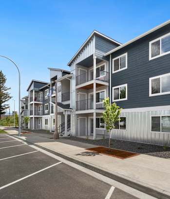 A modern apartment complex with a parking lot in front.