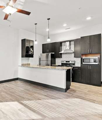 A modern kitchen with a white island and black cabinets.