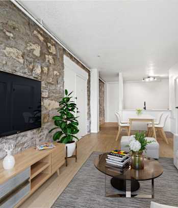 A living room with a stone wall and a flat screen TV at Tallmadge Lofts in Denver, CO 80211