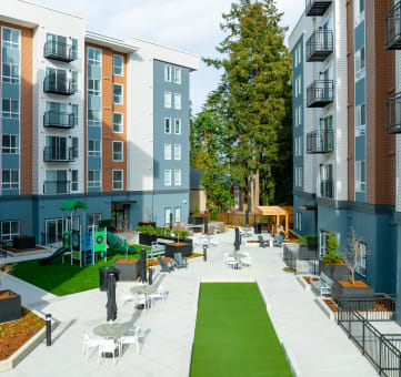 an outdoor patio with tables and chairs in front of an apartment building
