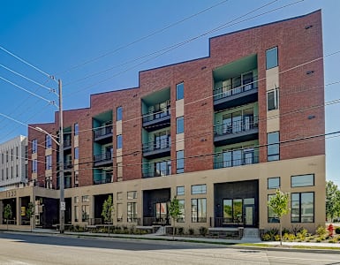 a red brick apartment building with green balconies