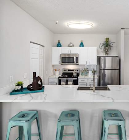 A kitchen with a white counter and blue stools.