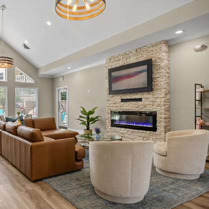 A living room with a stone fireplace and a television mounted above it.