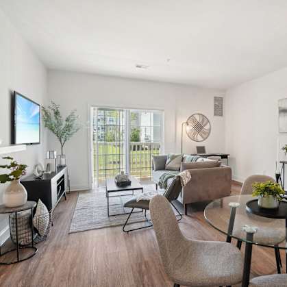 A modern living room with a glass table and grey chairs.