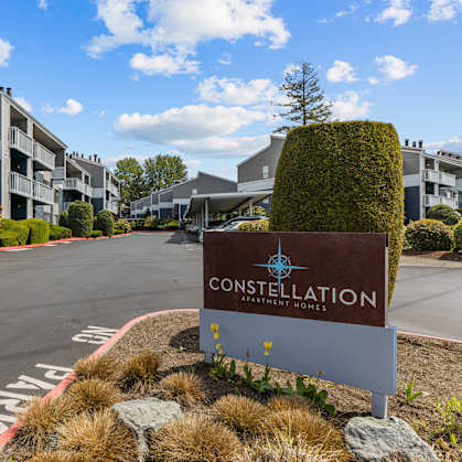 A sign for Constellation Apartments is in the foreground of a road.