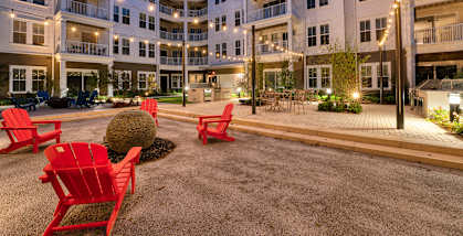 a courtyard with red chairs in front of an apartment building