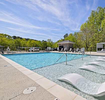 a resort style pool with lounge chairs and umbrellas