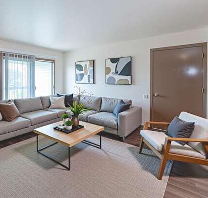 A living room with a grey couch, a wooden coffee table, and a wooden chair.