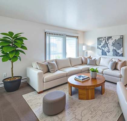 A living room with a white couch, a coffee table, and a plant.