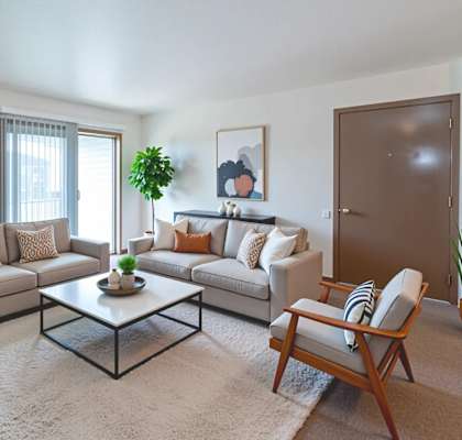 A living room with a grey couch, a coffee table, and a wooden chair.