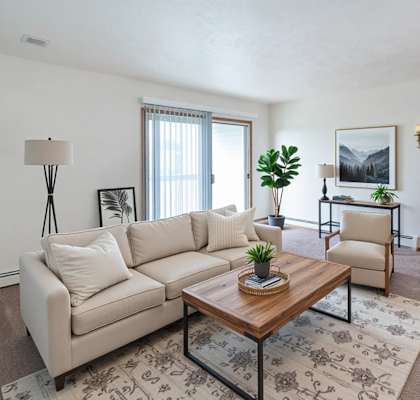 A living room with a beige couch, a wooden coffee table, and a rug with a floral pattern.