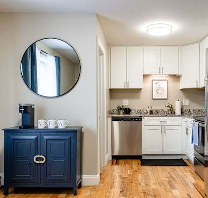 A kitchen with a blue cabinet and a round mirror on the wall.