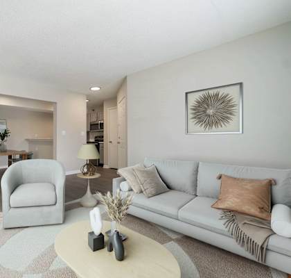 A living room with a grey couch, a white coffee table, and a grey armchair.