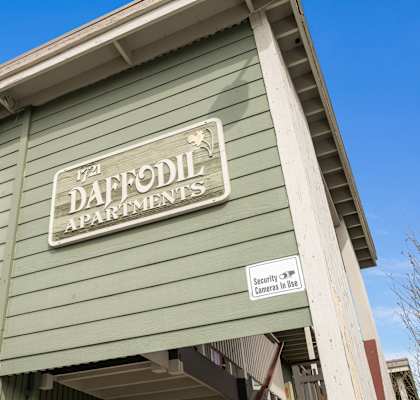 A green building with a sign that says Daffodil Apartments.