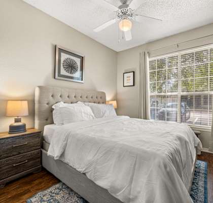 A bedroom with a bed, nightstand, and window.