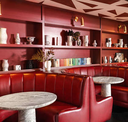 the interior of a restaurant with red leather booths and tables