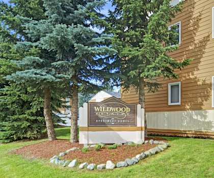 A brown building with a sign that says Wildwood Apartments.