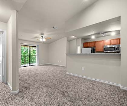 A spacious living room with a kitchenette in the background.