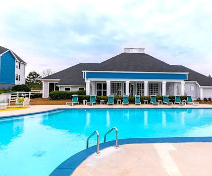 A swimming pool in front of a house with a blue roof.